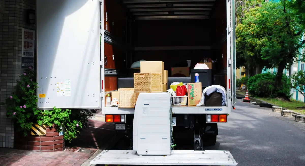 Camion de déménagement chargé de cartons et de mobilier devant un immeuble résidentiel